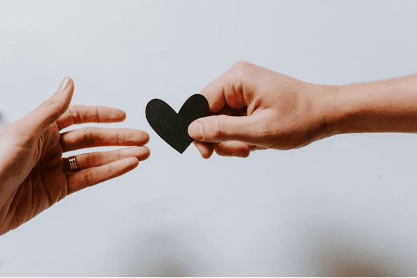 Love Languages: How to Use Acts of Service in Your Relationship 6 person reaching black heart cutout paper